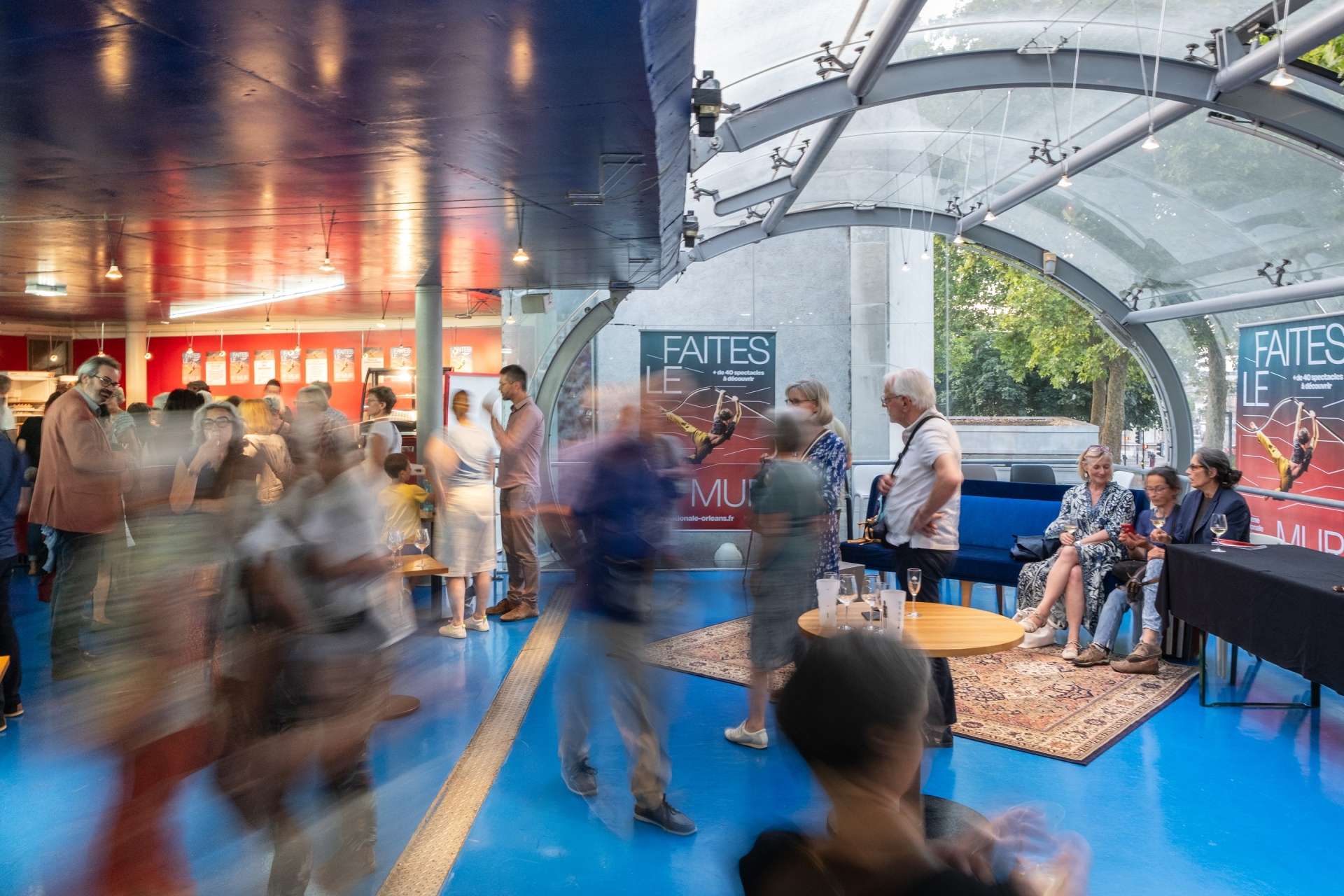 Photo du public après la présentation de saison, pendant le pot au bar de la passerelle. Jeu de flou sur l'image. 