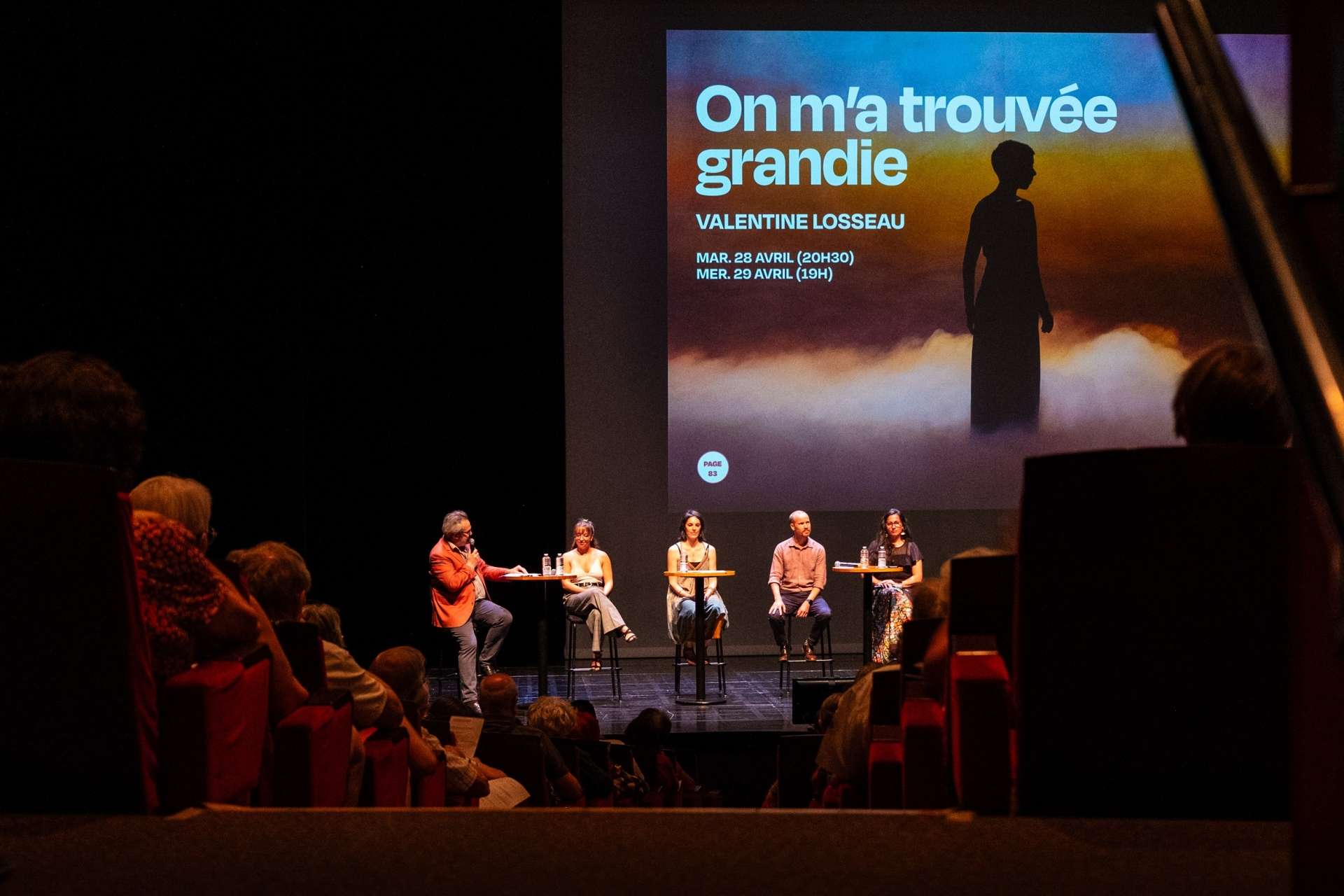 Photo de la salle Touchard comble avec sur scène cinq membres de l'équipe qui présentent le spectacle On m'a trouvée grandie lors de la présentation de saison. 