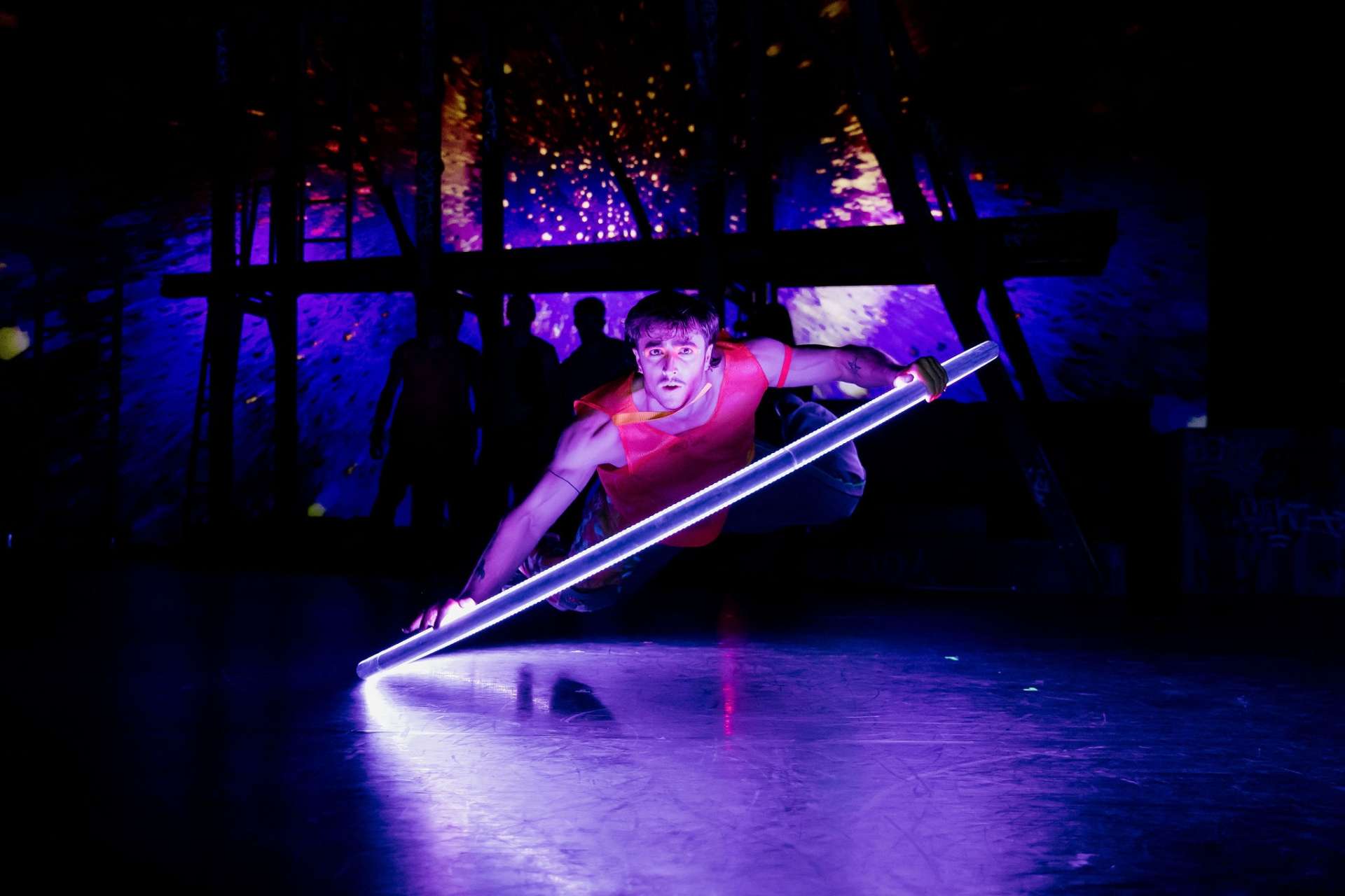 Dans un incroyable jeu de lumière, un artiste circassien est en train de pratiquer la roue cyr, sorte de grand cerceau. 