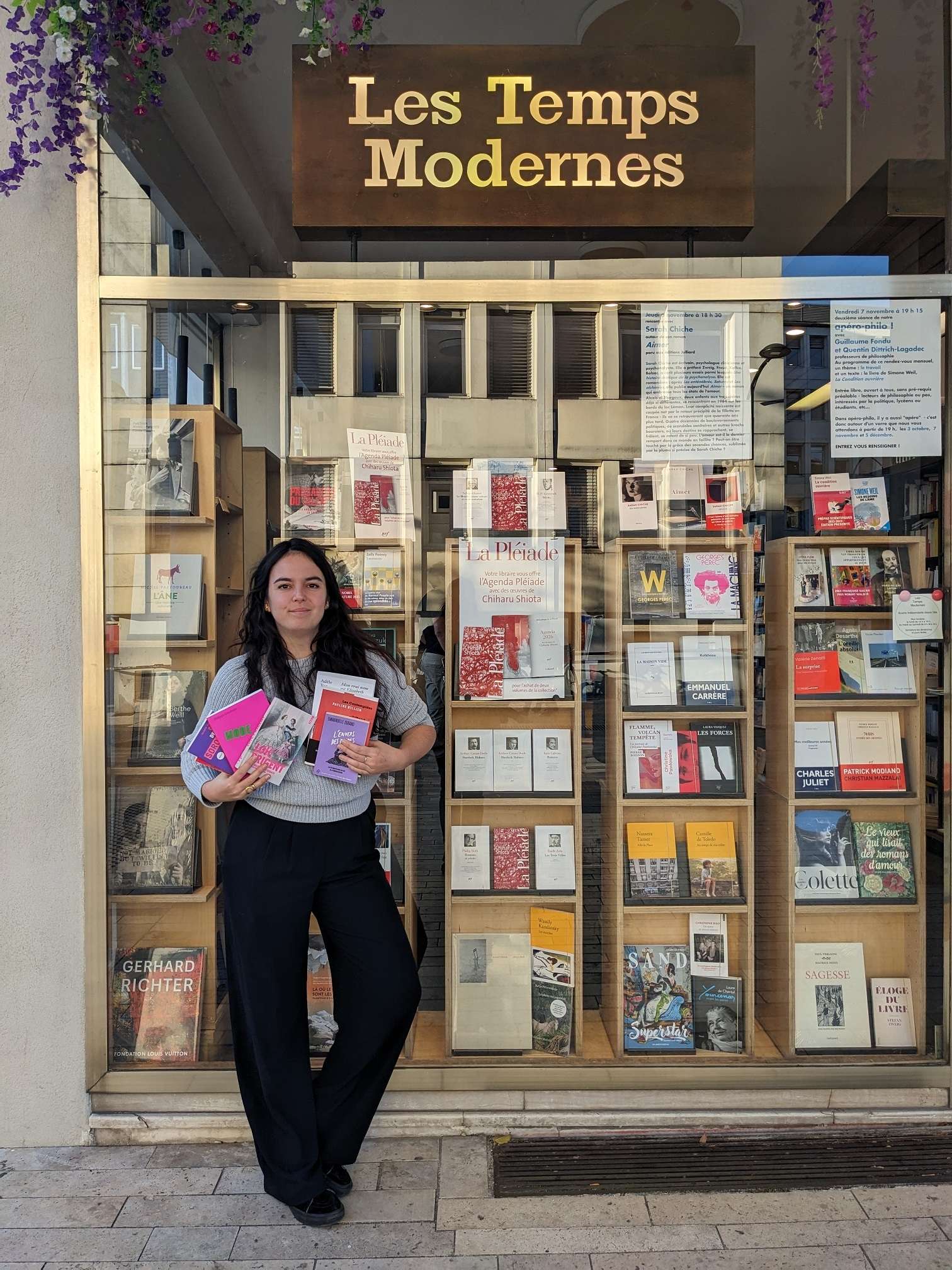 Photo de la libraire Deborah Vedel posant devant la devanture de la Librairie Les Temps Modernes. 