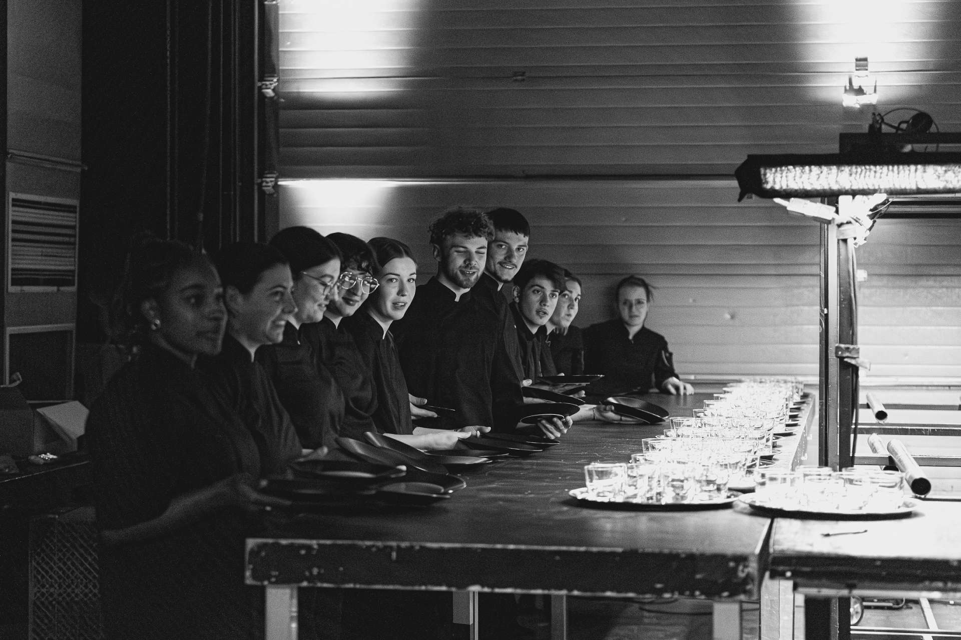 Photo noir et blanc. Les élèves tiennent des assiettes et sont prêts à servir. 