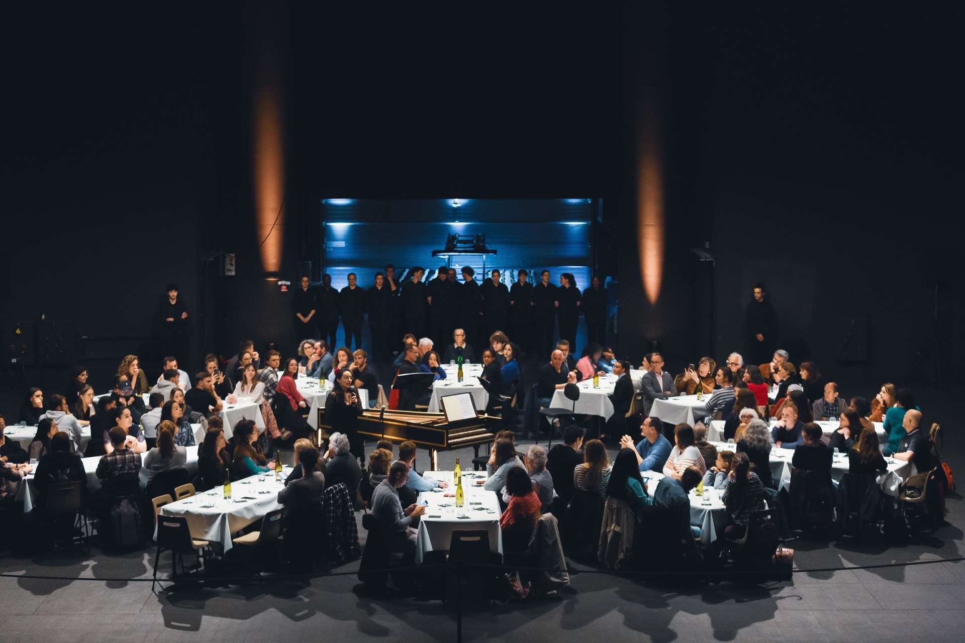 Plan large où l'on aperçoit les convives installés à leurs tables et au centre notre collègue Salomé Lelait qui est train de faire un discours. Les pâtissiers sont visibles en fond de salle. Il y a une jolie ambiance lumineuse. 