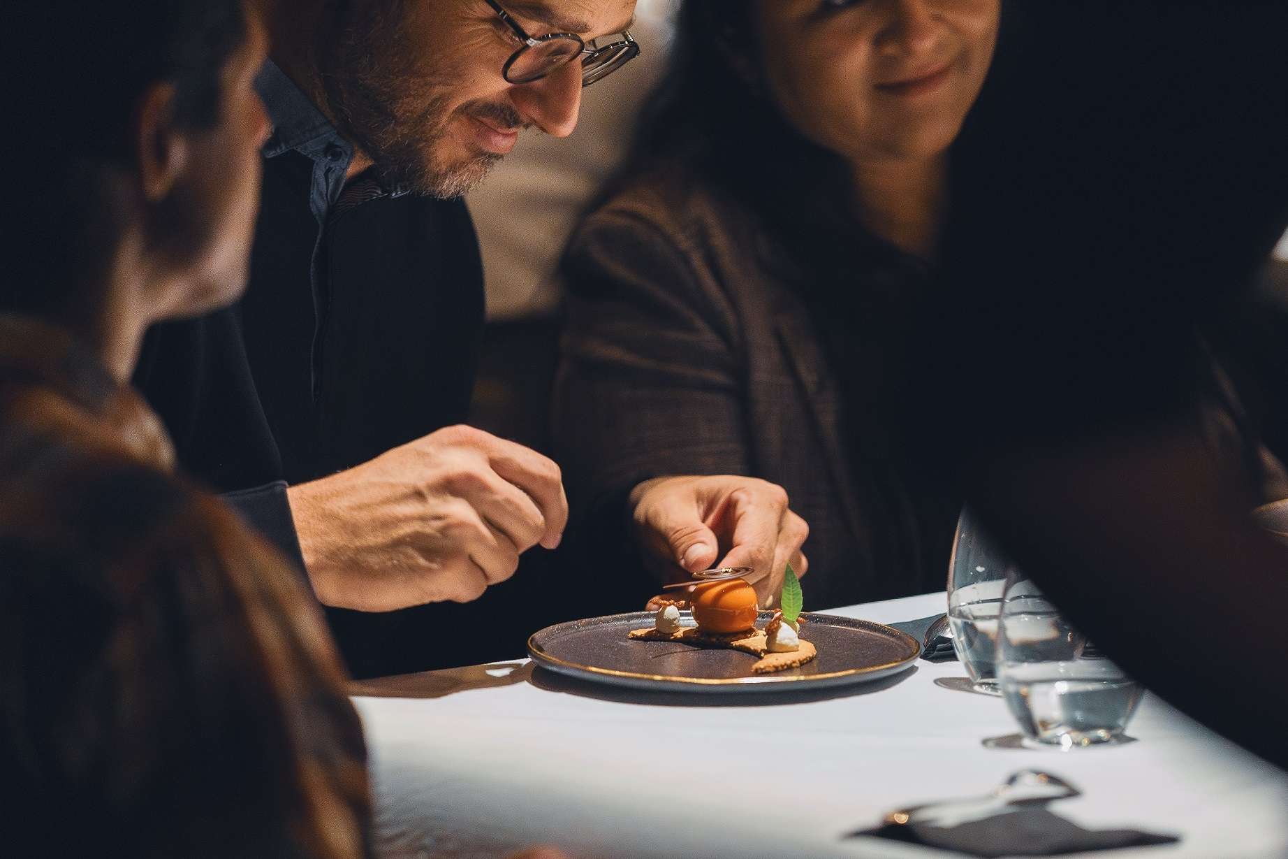Un monsieur portant des lunettes est sur le point de déguster la pâtisserie La nuit orientale. 