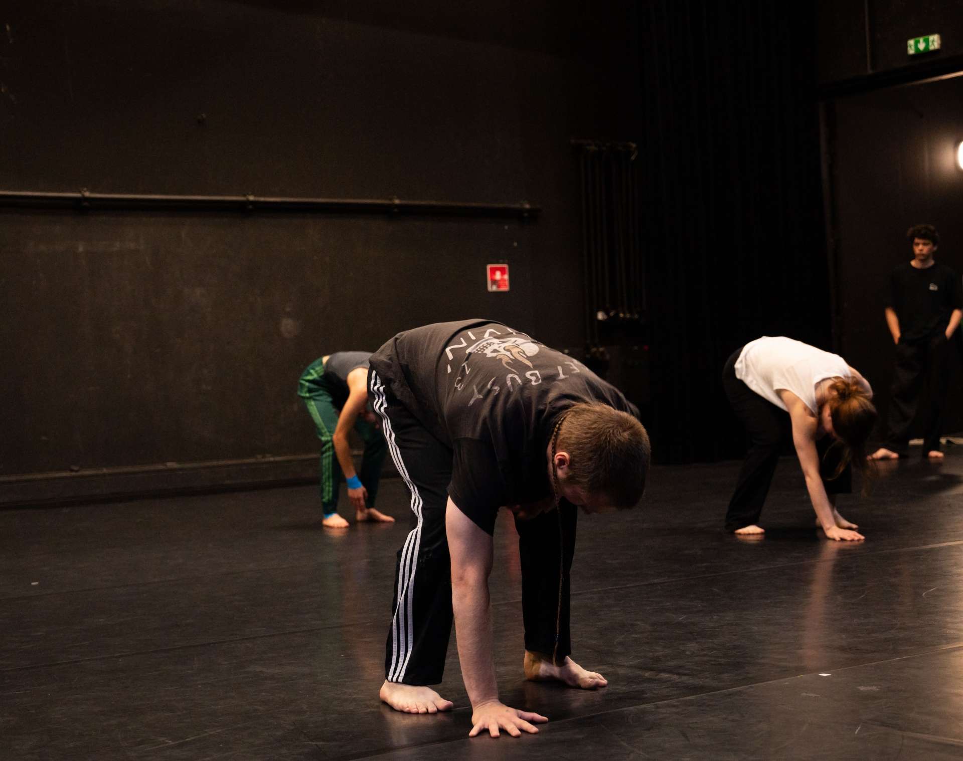 Photo de l'atelier de danse acrobatique, Clotaire et les autres participant·es sont penchant en avant et touchent leurs pieds.